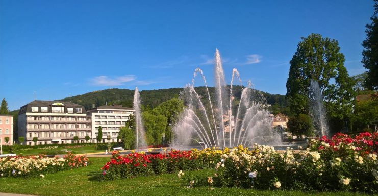 Rosengarten, Brunnen mit Wasserfontänen umgeben von bunten Rosenstöcken.