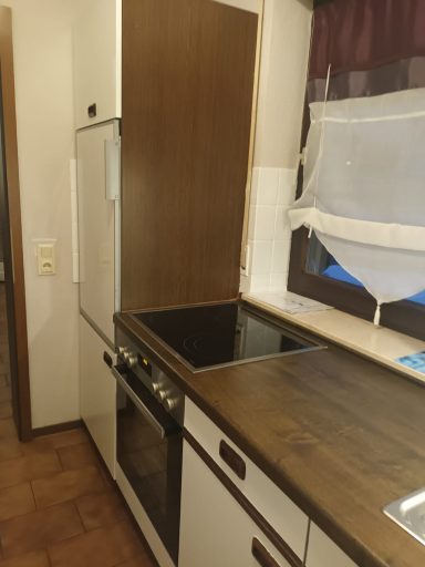 Küche hell und freundlich Moderne Küche mit Holzarbeitsplatte, Herd und Kühlschrank in hellen Farbtönen.